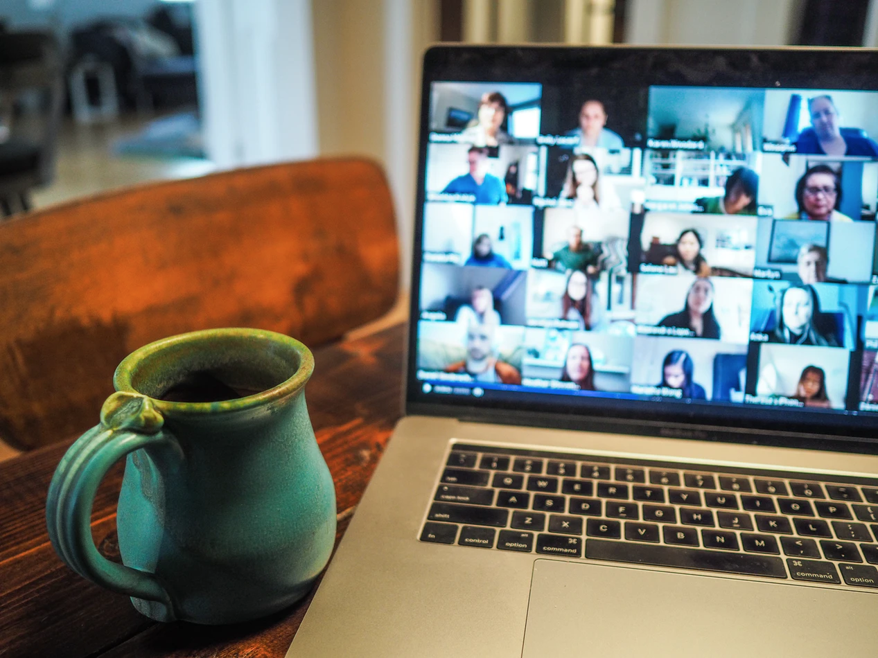 A cup next to a laptop showing participants on a video call